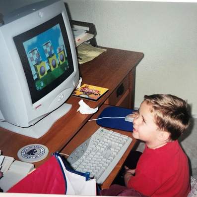 a picture of Joe as a child playing a game on one those big, boxy old desktop computers